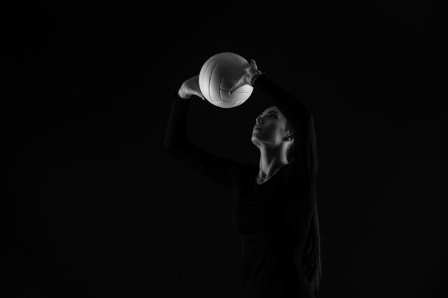 Volleyball girl serve ball on dark background. Player doing sport workout online. Sport and recreation concept. Black and white color filter