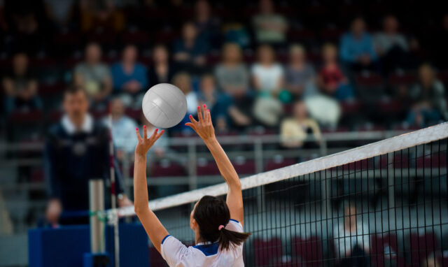 Girl Volleyball player and setter setting the ball for a spiker during a game